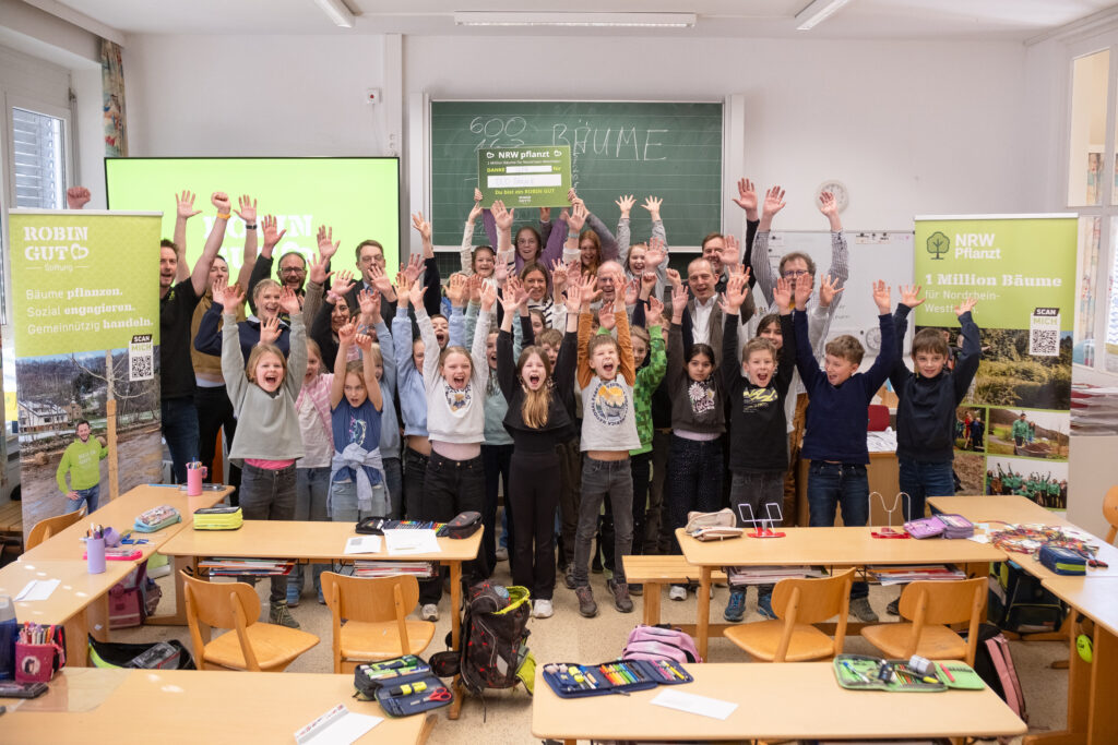 Gemeinsam mit Lehrkräften und Unterstützern feiern die Schülerinnen und Schüler ihre Baumspende im Klassenraum und engagieren sich aktiv für die Wiederaufforstung in Nordrhein-Westfalen. Die Aktion „NRW pflanzt“ fördert den Erhalt heimischer Wälder und motiviert junge Menschen, Verantwortung für Umwelt und Zukunft zu übernehmen.